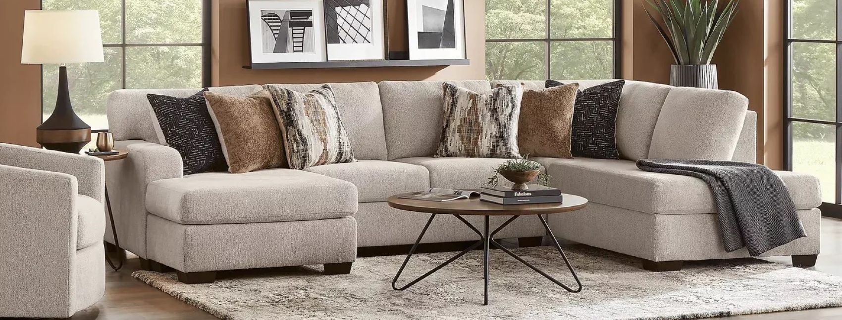 Beige sectional sofa with decorative pillows and a round coffee table.

