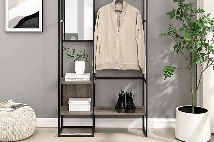 A black metal and wood hall tree with a jacket, boots, and a plant.
