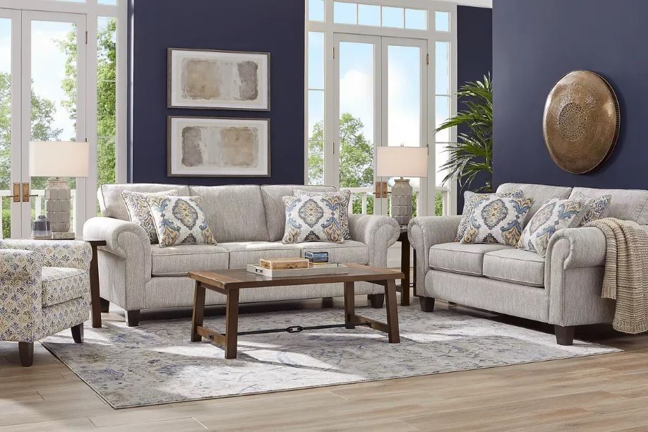Living room with gray sofas, patterned pillows, and a wooden coffee table on a patterned rug.
