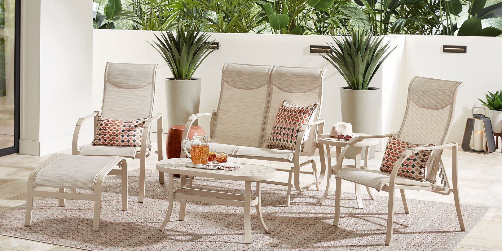 Photo of beige patio seating set with loveseat, chairs, ottoman and tables